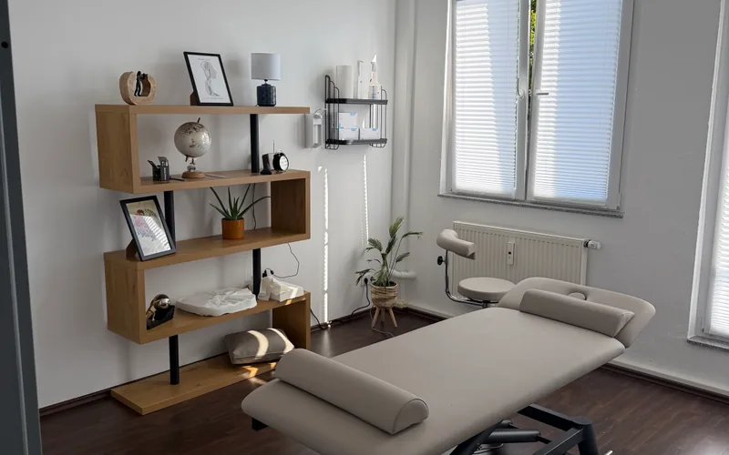 Behandlungsraum mit Liege und offenem Holzregal im Klinikviertel