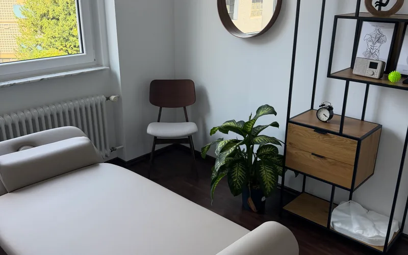 Behandlungsraum mit Liege, Spiegel und Grünpflanze im Klinikviertel